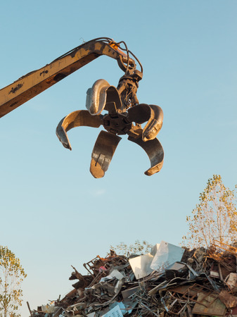 crane with open claw on top of pile with scrap metalの写真素材