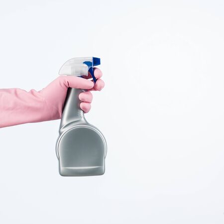 human hand with protective glove holding cleaning spray bottle. isolated on whiteの写真素材