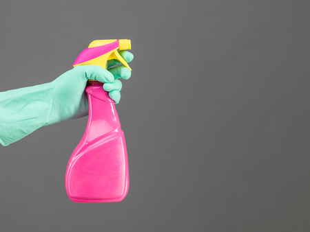 hand with rubber glove holding cleaning spray container on grey background, copy space availableの写真素材