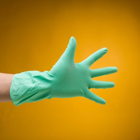 hand in rubber glove with yellow backgroundの写真素材