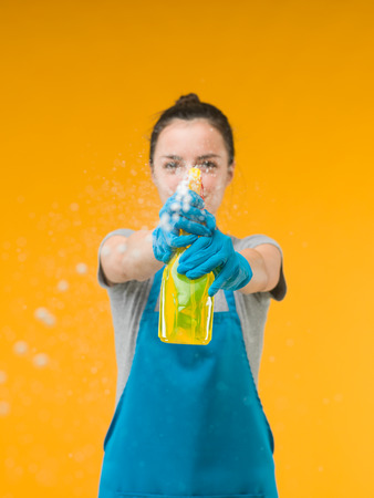 woman spraying cleaning detergent on surface in front of herの写真素材
