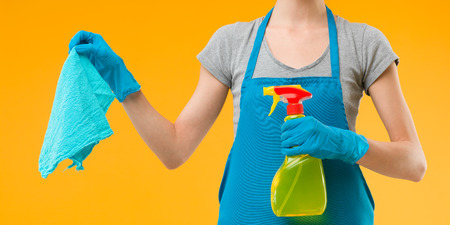 close-up of maid holding cleaning products against yellow backgroundの写真素材