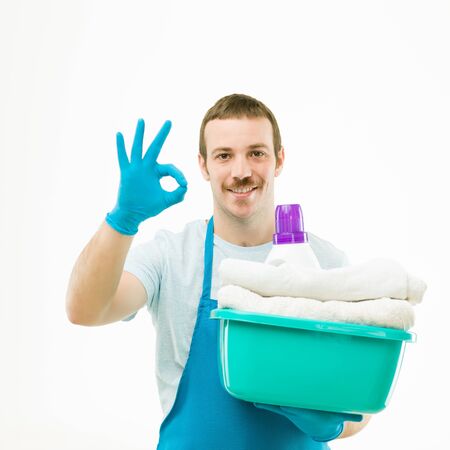 portrait of caucasian man holding basket with laundry, smiling and showing ok sign, on white backgroundの写真素材