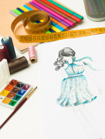 closeup of fashion designer workspace with sketches and designing equipmentの写真素材