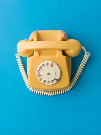 upper view of yellow vintage phone on blue backgroundの写真素材