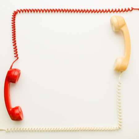 two handsets from vintage phones facing each other arranged in a square shape, on white backgroundの写真素材