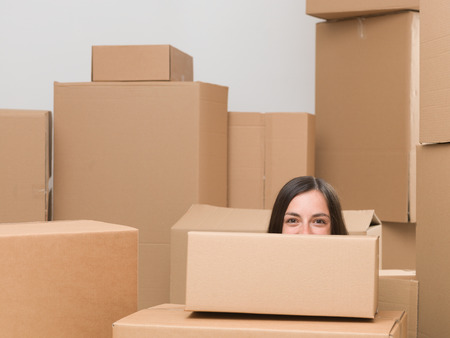 happy woman surounded by cardboard boxes only seeing half of her head