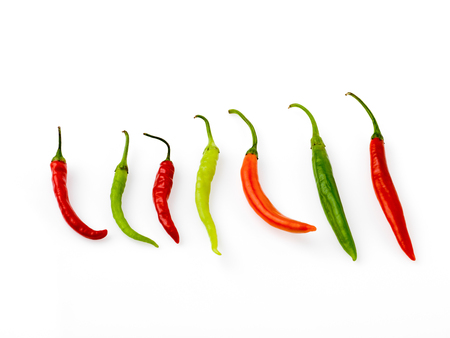 peppers of various colors arranged in line on withe backgroundの写真素材