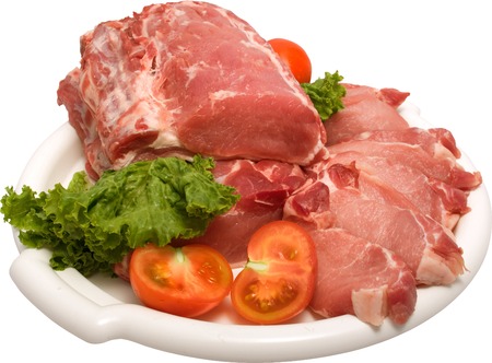 white plate containing raw meat with white streaks of fat, lettuce leaves and cherry tomatoes on the sideの写真素材