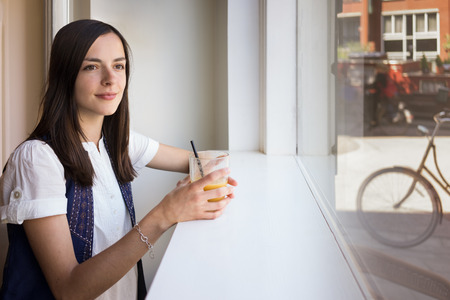 Beautiful young woman relaxes in a café in the center 's Amstrerdam holding a glass of fresh orange morningの写真素材