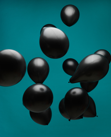 black balloons floating in fron of a blue backgroundの写真素材