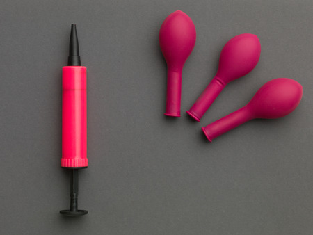 pink balloon pump near three pink balloons,  on a grey backgroundの写真素材