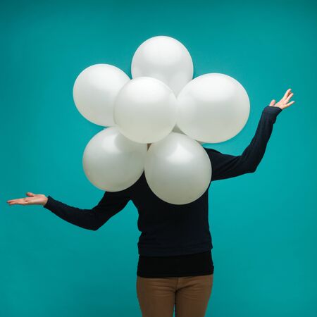 funny young woman with a flower made  from balloon in front of her on blue backgroundの写真素材