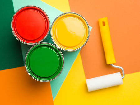 three cans  yellow green and red and paint roll on colourful geometrical backgroundの写真素材