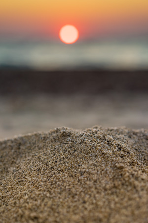 Blur tropical sunset beach with bokeh light sand abstract texture backgroundの写真素材