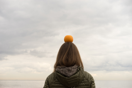 woman with orange on her head with ocean backgroundの写真素材