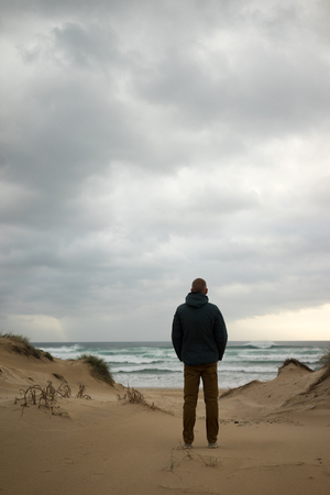 Man standing at the shore, looking at the waves in the sea.の写真素材