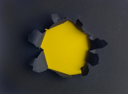 Black sheet of paper with a round hole  yellow background insideの写真素材