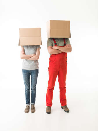 woman and man standing with hands crossed against their chests, hiding their heads under cardboard boxes. on white backgroundの写真素材