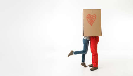 couple embracing and kissing each other, being covered by big box. on white backgroundの写真素材