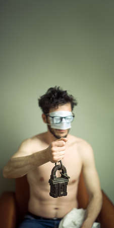 Men holding a lock-pad during carantine, mask on his eyesの写真素材