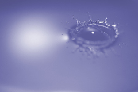 Smooth Water surface broken by single droplet with an even splash circle