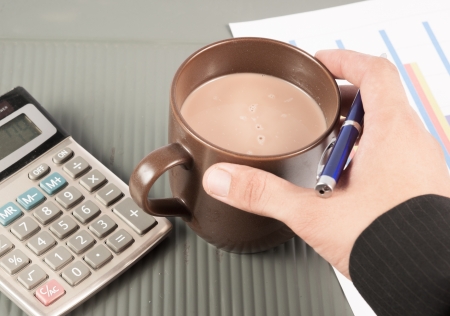 Close-up image of an office desk at morning with a cup of tea and financial documentsの写真素材