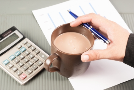 Close-up image of an office desk at morning with a cup of tea and financial documentsの写真素材
