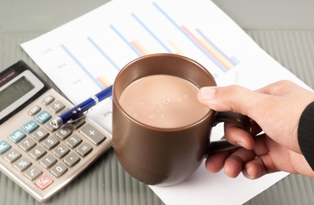 Close-up image of an office desk at morning with a cup of tea and financial documentsの写真素材