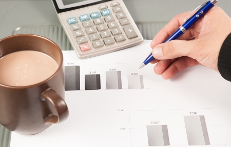 Close-up image of an office desk at morning with a cup of tea and financial documentsの写真素材