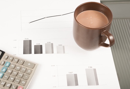 Close-up image of an office desk at morning with a cup of tea and financial documentsの写真素材