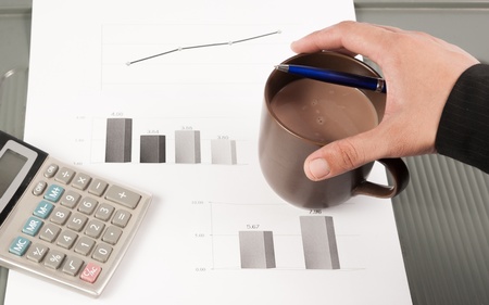Close-up image of an office desk at morning with a cup of tea and financial documentsの写真素材