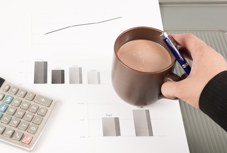 Close-up image of an office desk at morning with a cup of tea and financial documentsの写真素材