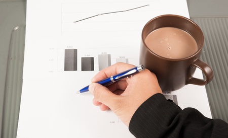 Close-up image of an office desk at morning with a cup of tea and financial documentsの写真素材