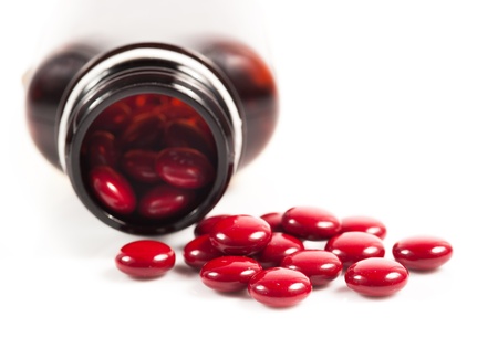 Red pills and pill bottle on whiteの写真素材
