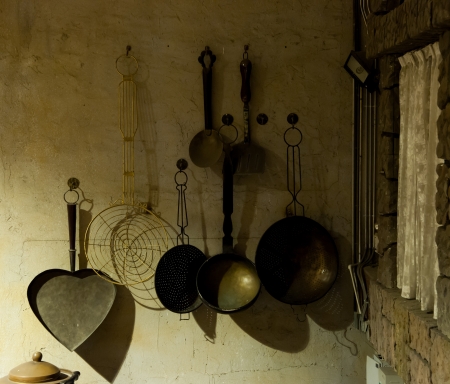kitchenware hanging in the kitchen of an old country house - retro equipment of old timesの写真素材