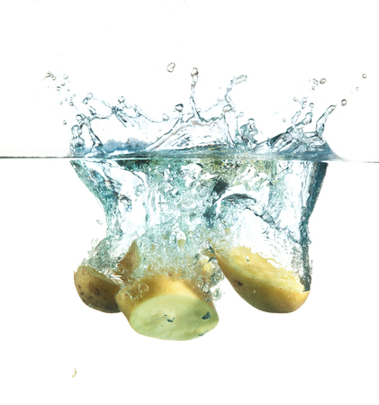 potatoes splashing into water against a whiteの写真素材
