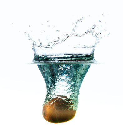 Fresh kiwi fruit splashing in the water isolated on white with bubblesの写真素材