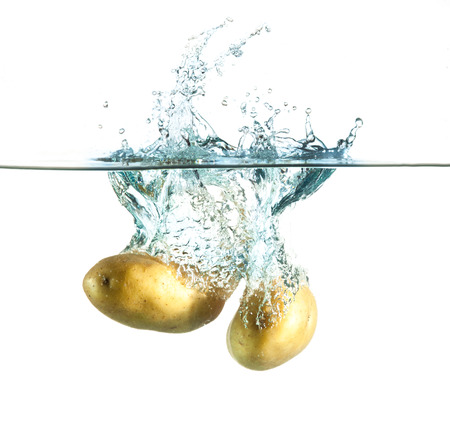 potatoes splashing into water against a whiteの写真素材