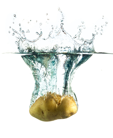 potatoes splashing into water against a white background.の写真素材