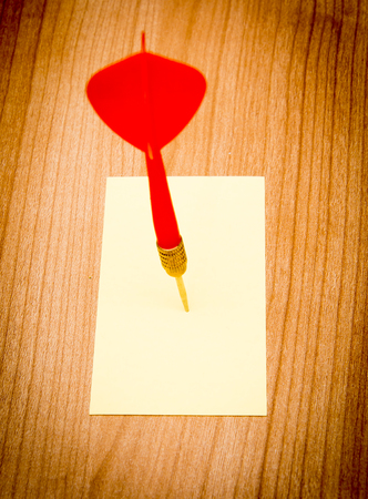 Red darts in an empty or blank notepad on a vintage wooden boardの写真素材