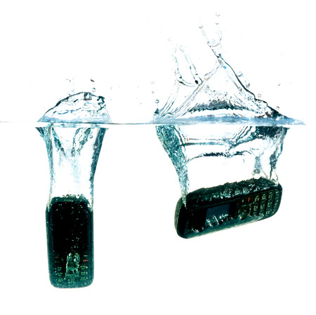 Phone splashing into water against a white backgroundの写真素材