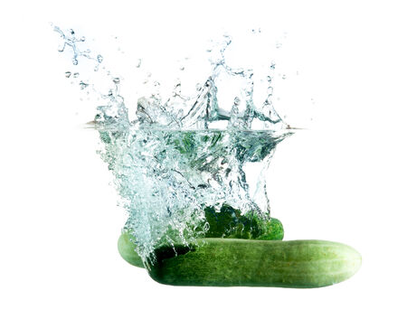 green cucumbers dropped into water isolated on whiteの写真素材