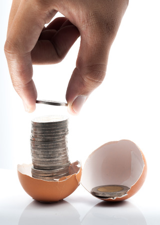 hand keep coin on broken eggshellの写真素材