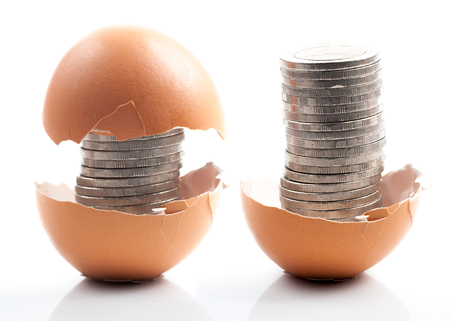 Coins in broken golden eggshell 
