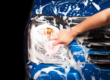 man washing a soapy blue car with a pink sponge.の写真素材