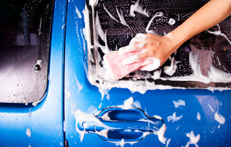 hand hold sponge over the car for washingの写真素材