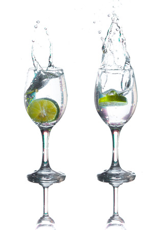 Lime splashing into glass of water on white backgroundの写真素材