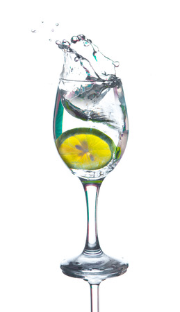 Lime splashing into glass of water on white backgroundの写真素材