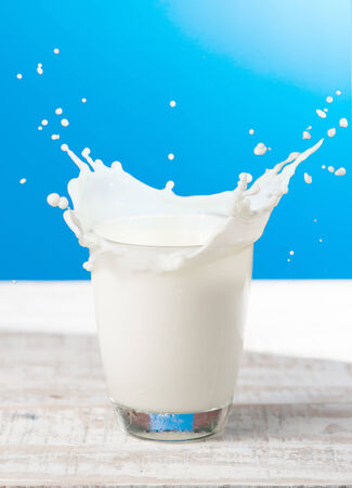 Splash of milk from the glass on a blue backgroundの写真素材